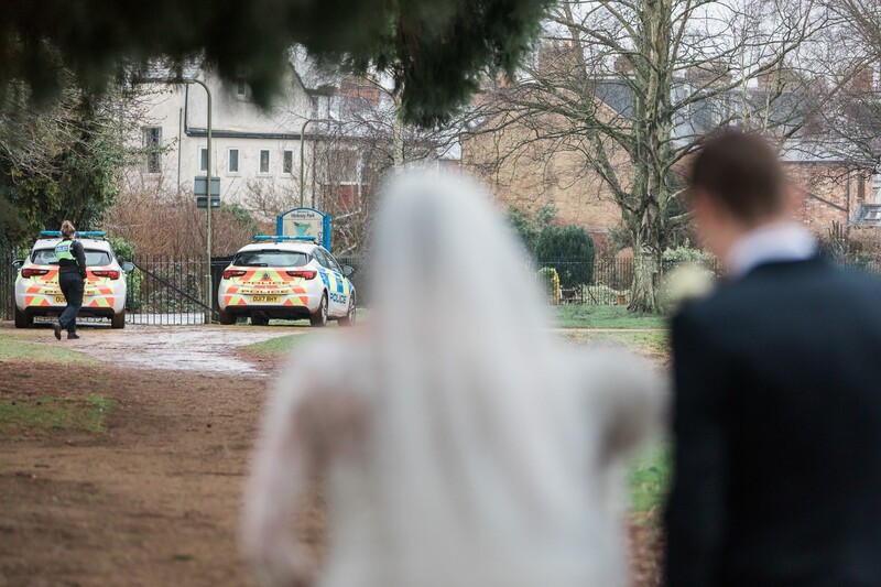 Bride and groom looking at police cars.