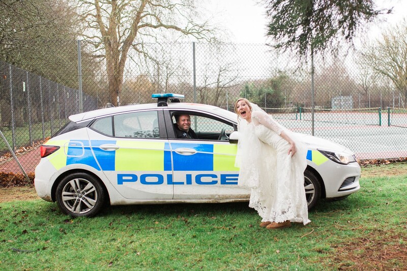 Bride posing with a police car.