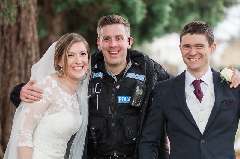 Bride and groom posing with a policeman.