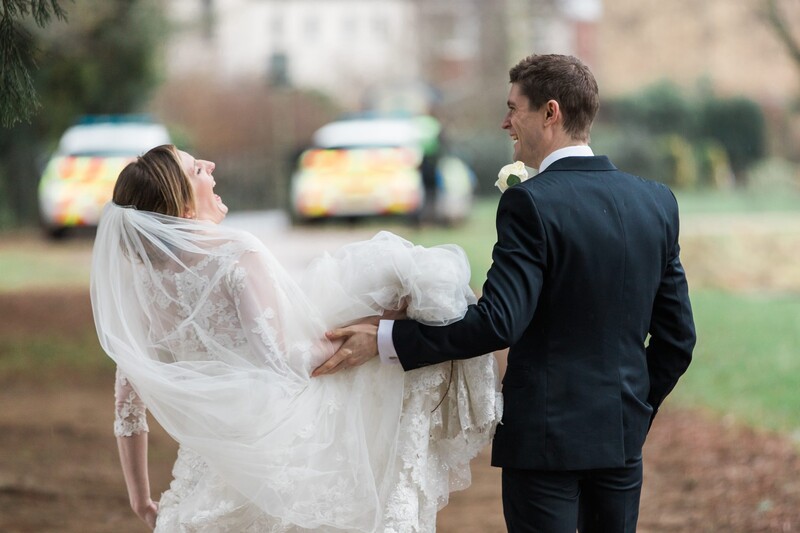 Bride and groom facing police cars.
