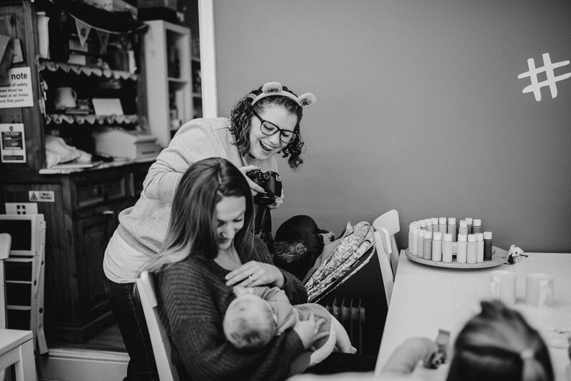 Female photographer documenting breastfeeding mother.