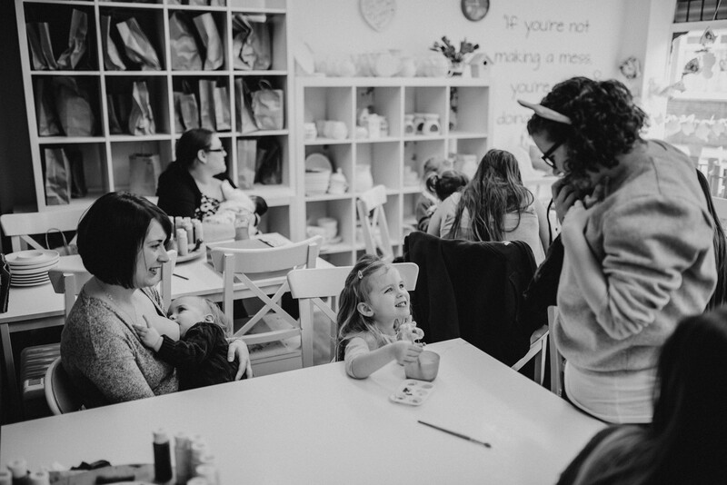 Female photographer engaging with a child and a breastfeeding mother.
