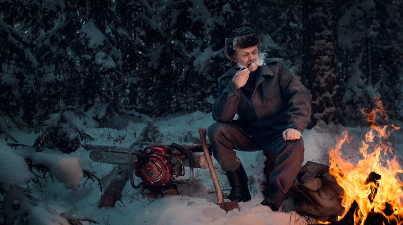 Lumberjack smoking a pipe by a fire.