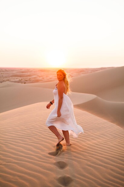 Girl walking in a dessert wearing a white dress