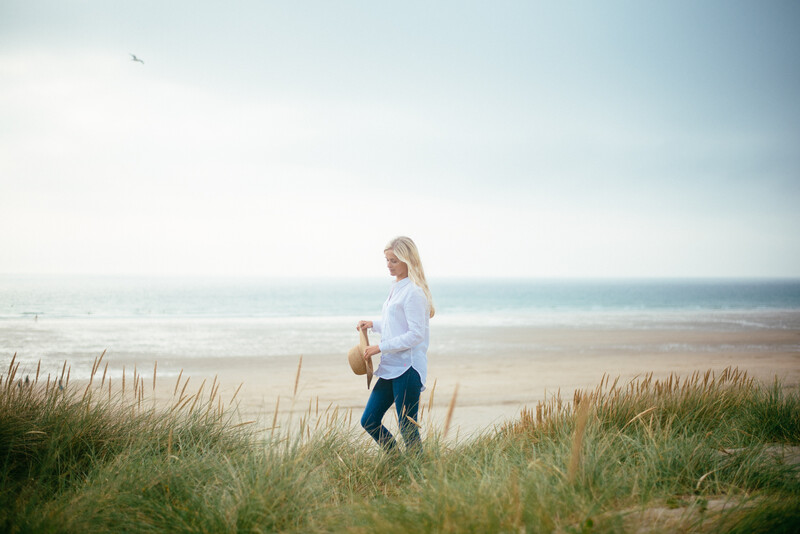 Young blonde woman walking by a beach.