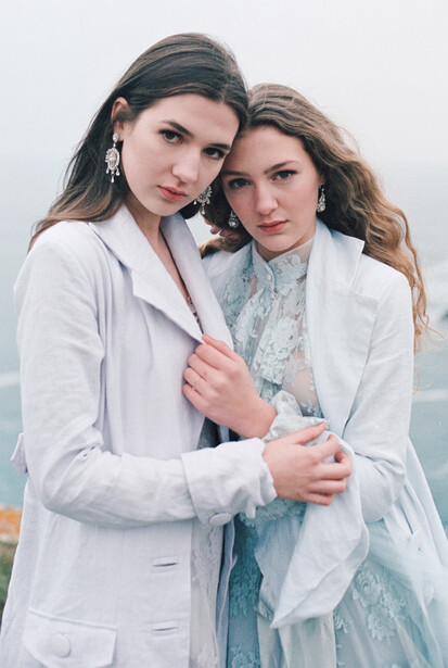 Two young brown haired women in pastel blouses.