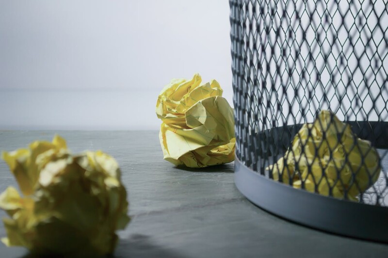 pieces of yellow crumped up paper next to a trash can