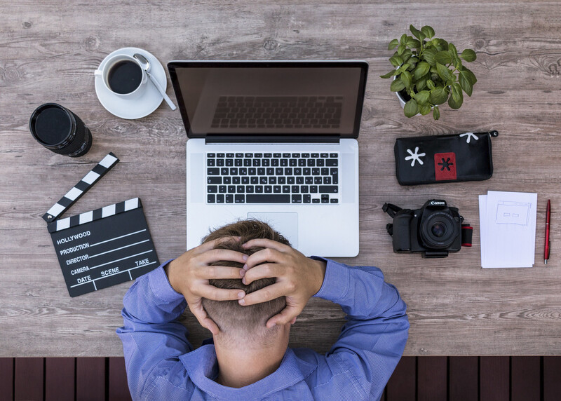 an overhead view of a man at his desk, hands on head in frustration