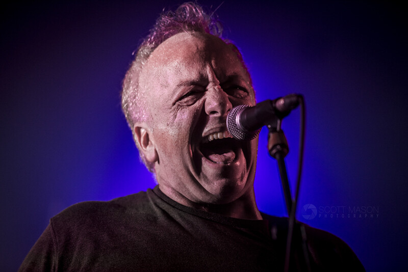 a close-up live photo of Gene Ween from the band Ween, singing
