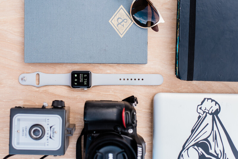 Smartwatch, laptop, camera and notebook on a table
