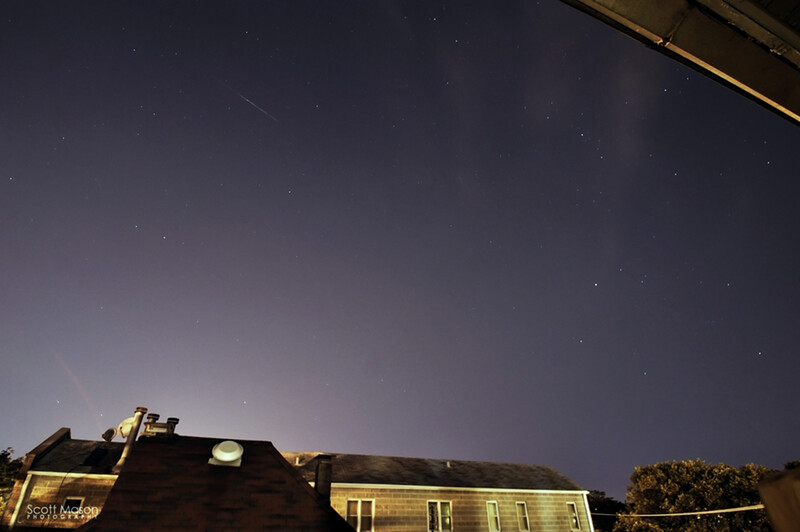 a meteor in the sky above a house in the city