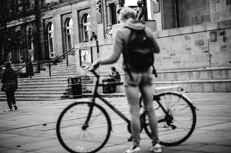 A street scene of a person on a bike and people in the background.