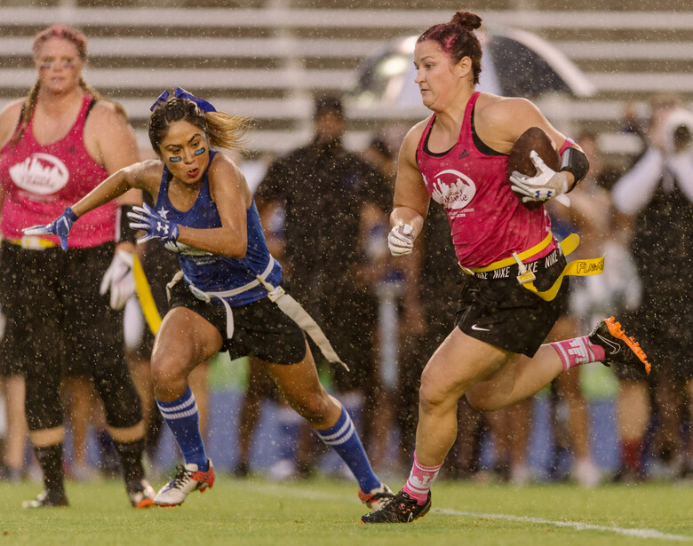 Football players run in the rain