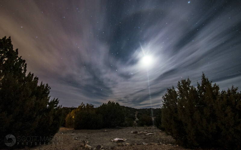 a photo of the moon with a halo around it with a desert landscape below