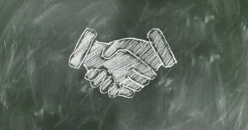 a photograph of a chalkboard with an illustration on it of two hands shaking
