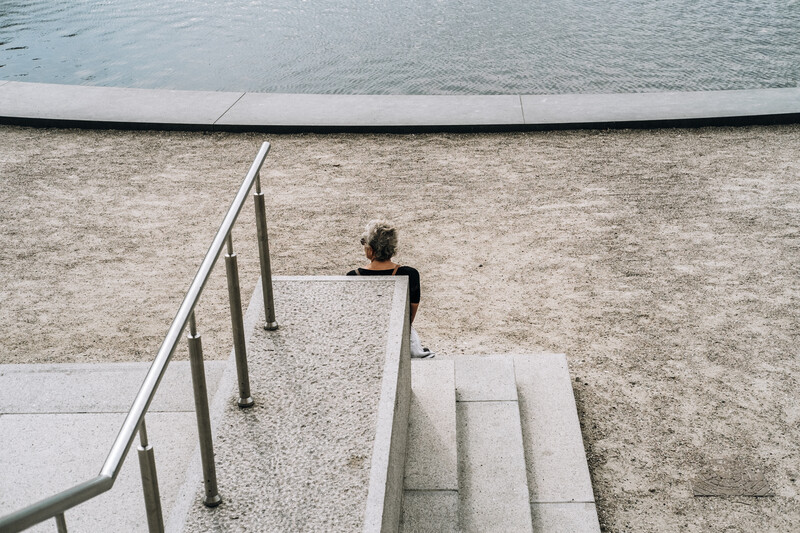 A silver haired woman sat at the bottom of steps.