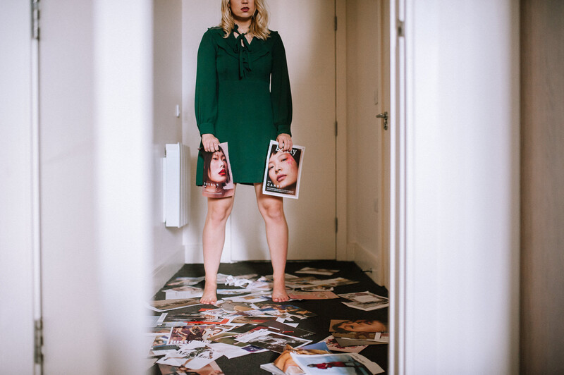 A young woman holding pages of a fashion magazine.