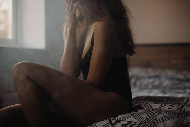 A young woman in a black bodysuit sat on the edge of the bed. 