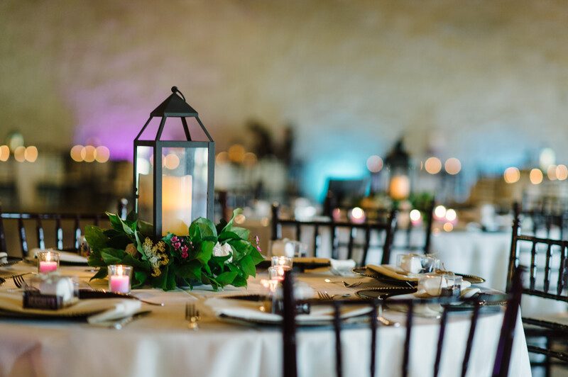 Lights, place settings, center pieces, and candles at a wedding