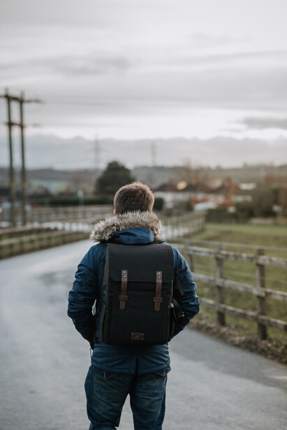 Man with a backpack walking down a country lane