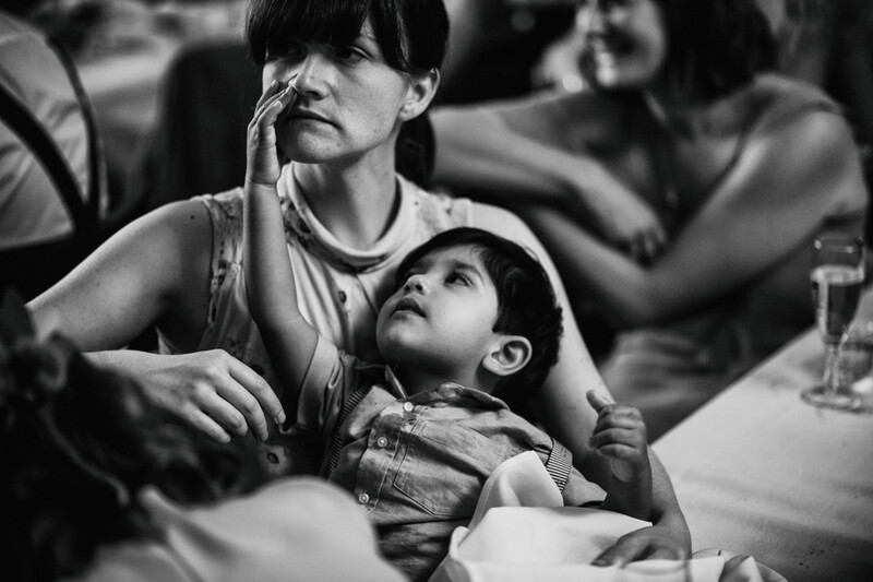 A child playing on his mother's lap at a wedding breakfast