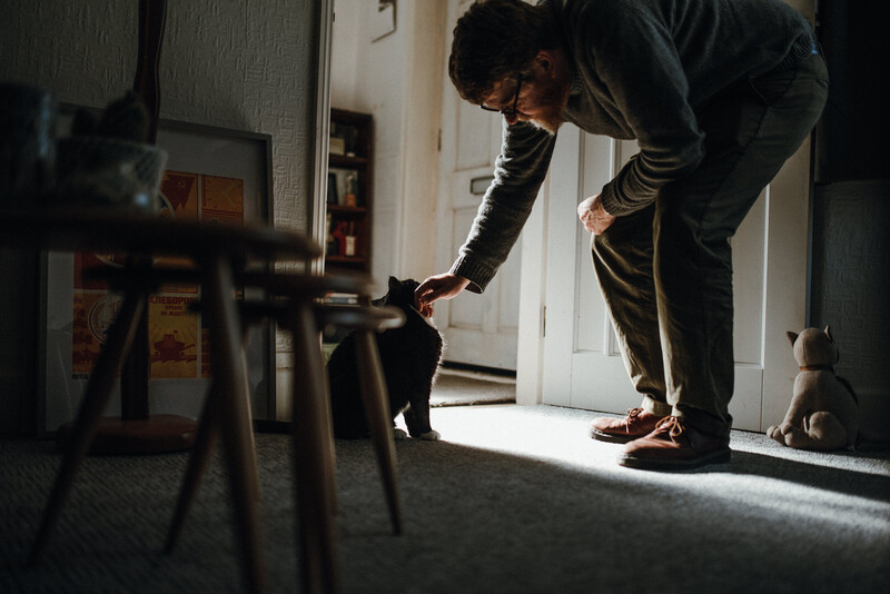 A man gently petting his black cat.