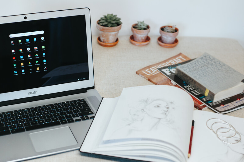 Workshop table with a laptop, notebook and books on it.