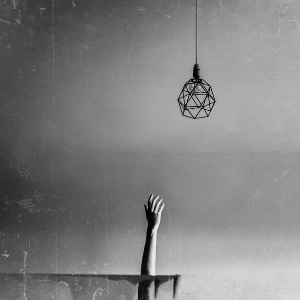 A hand reaching up towards the ceiling light.