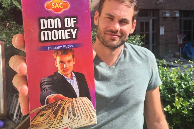 Lee Morris of Fstopper holding a leaflet with a photo of himself holding some twenty dollar bills.