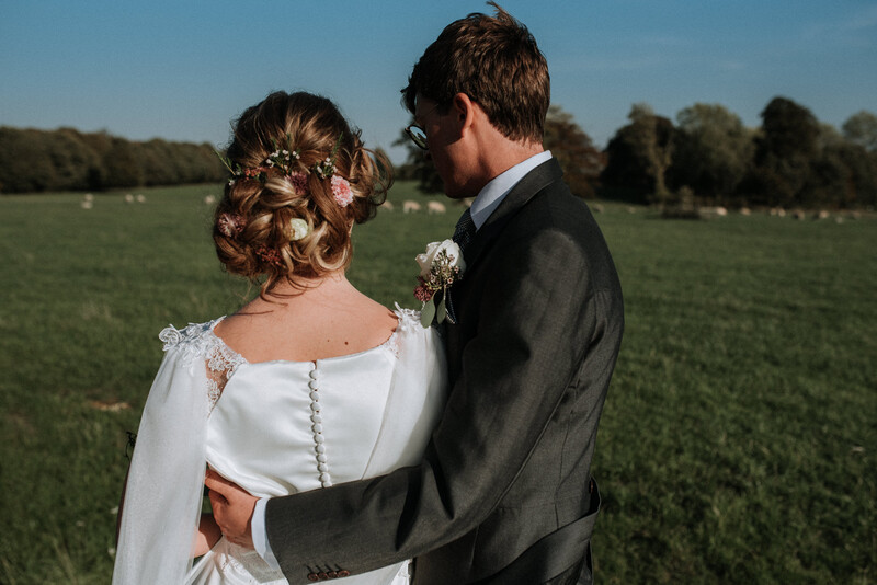 A bride and groom in a green field. 