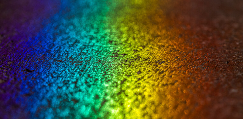 a macro photo showing a rainbow reflection on a surface close-up