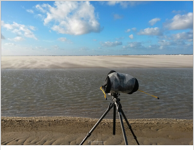 A rain cover can protect your gear and you still be able to use it. It not only protects against water, but sand also, like on a beach during a storm. You might also use a shower cap or plastic bag.