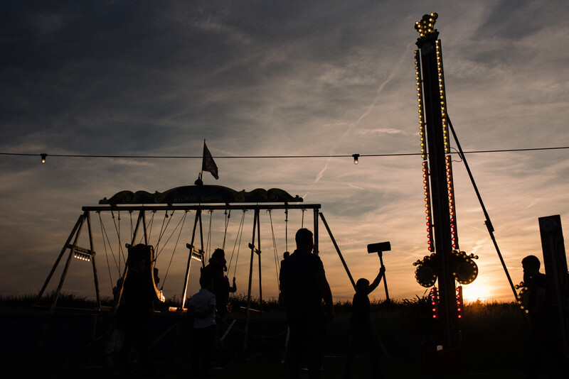 Children playing at a fairground during sunset.