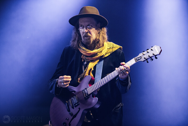 a guirarist on stage with lights behind him
