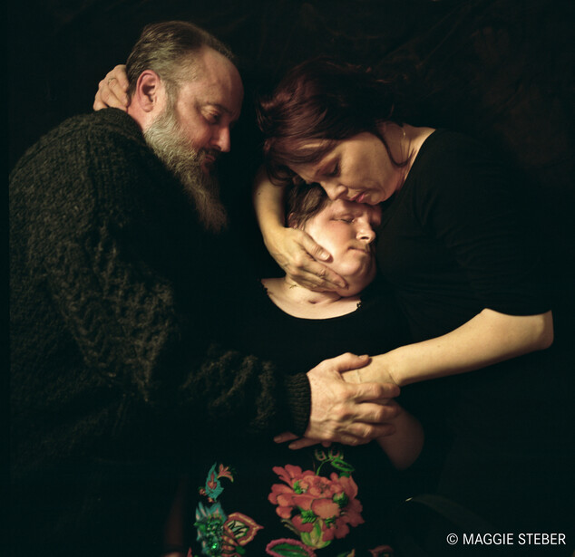Two parents hugging their child