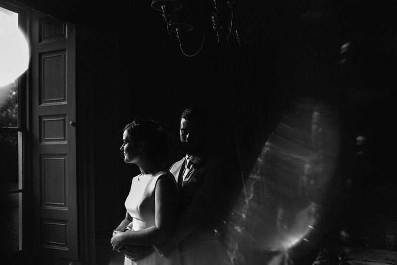 A groom hugging his bride from behind. 