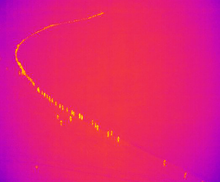 a thermal aerial photograph of rescuers walking down a path