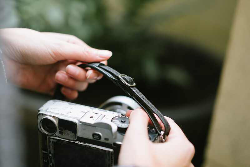 Fastening a black leather camera strap
