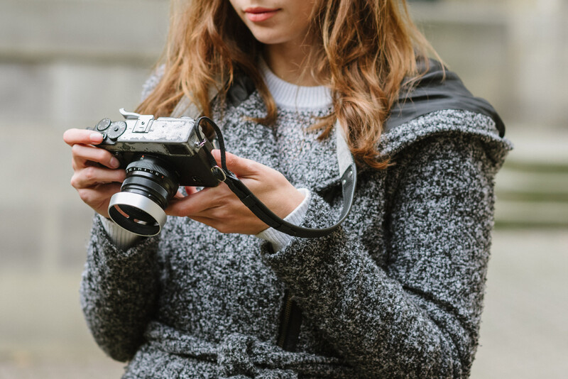 Holding a mirrorless Fuji with a black camera strap