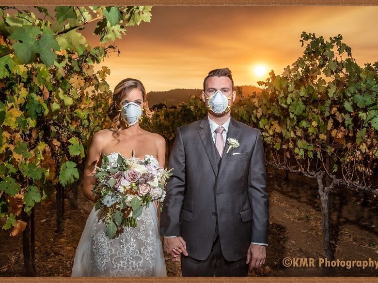 a wedding photo of a couple standing in front of the Kincade fire in California with masks on