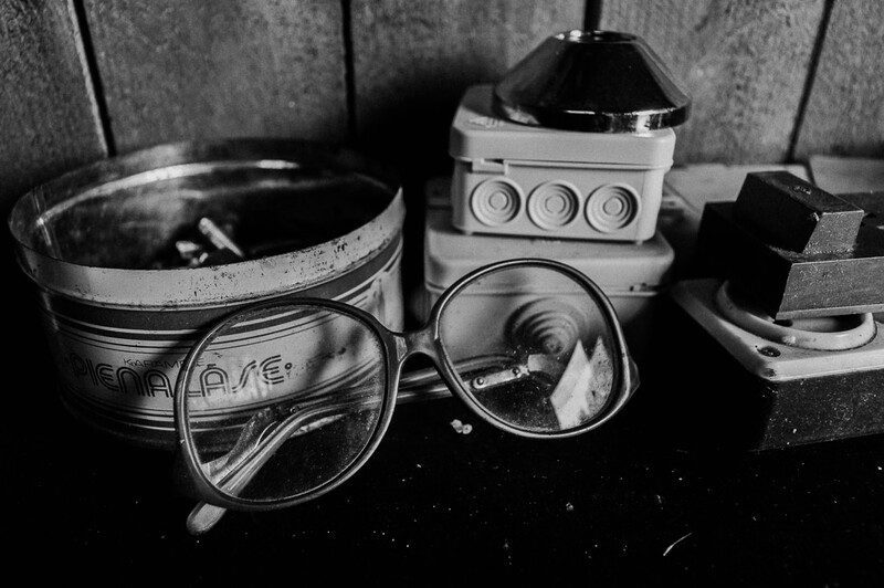 An old pair of glasses next to metal tins.