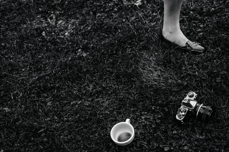Monochrome shot of a girl's shoe, tea cup and a camera