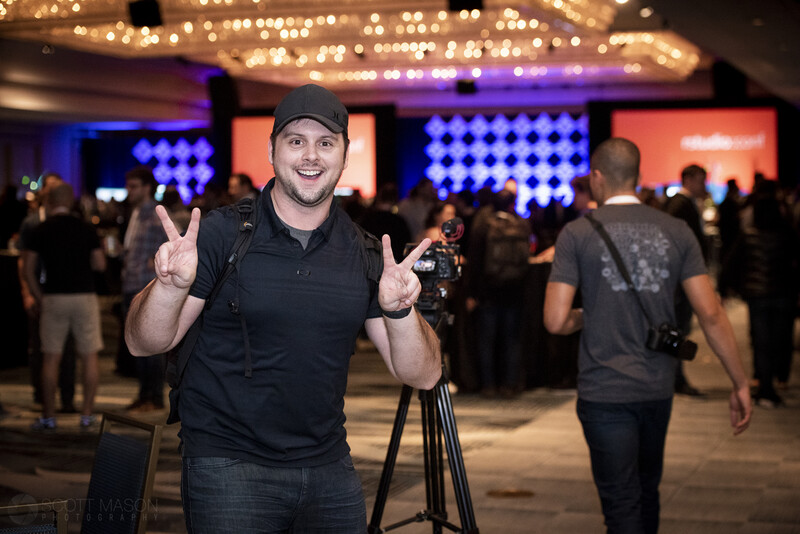 a videographer smiling and giving the peace sign at a conference