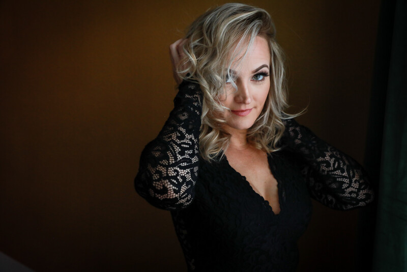 a woman with blonde hair posing in a lacey black dress