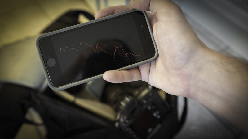 a hand holding an iPhone with a downtrending stock chart on its screen