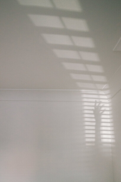 A shadow of a hand on a white wal.