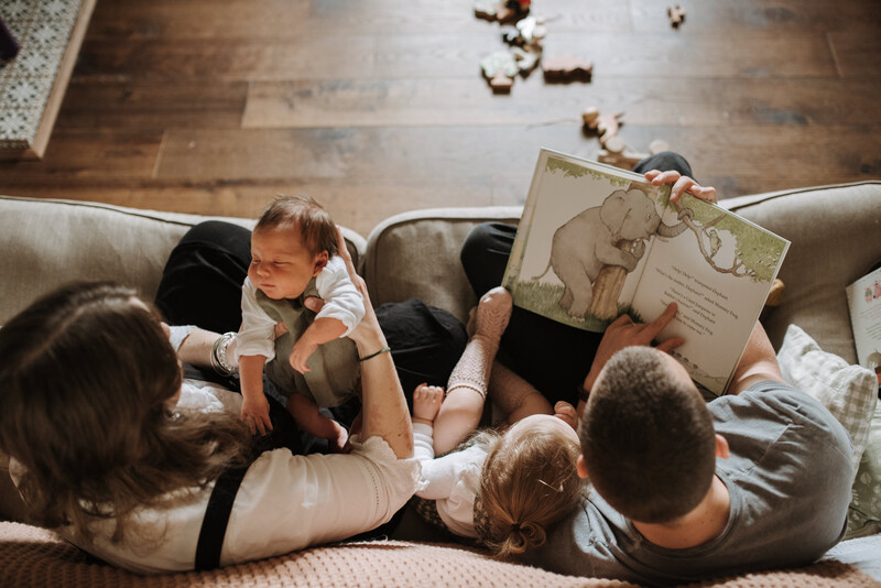 A young family reading a book together on the sofa.