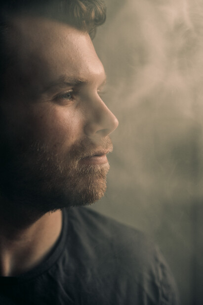 A bearded man in a smoky room.