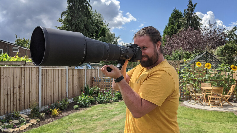 Man holding 600mm lens in garden