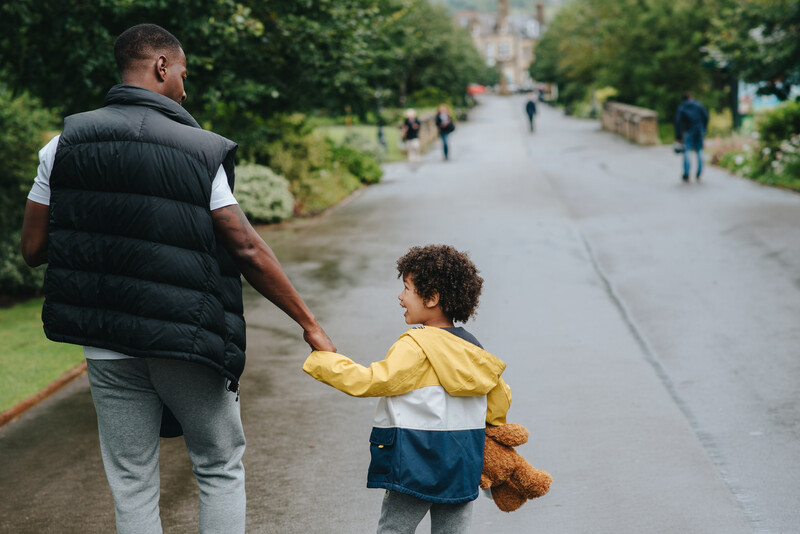 A father walking in the park with his young son.